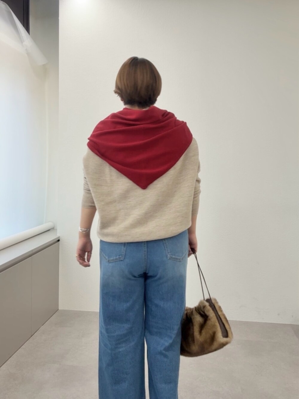 ベージュ系のニット/セーター、ブルー系のデニムパンツ、レッド系のストール/ショールを着用したレディースの冬コーディネートの5枚目の写真