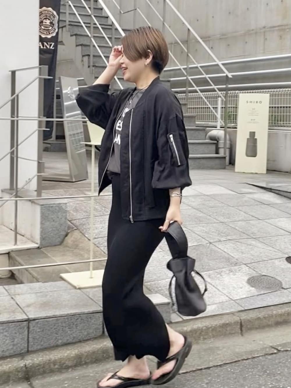 ブラック系のミリタリージャケット、グレー系のTシャツ/カットソー、ブラック系のスカートを着用したレディースの春コーディネートの2枚目の写真