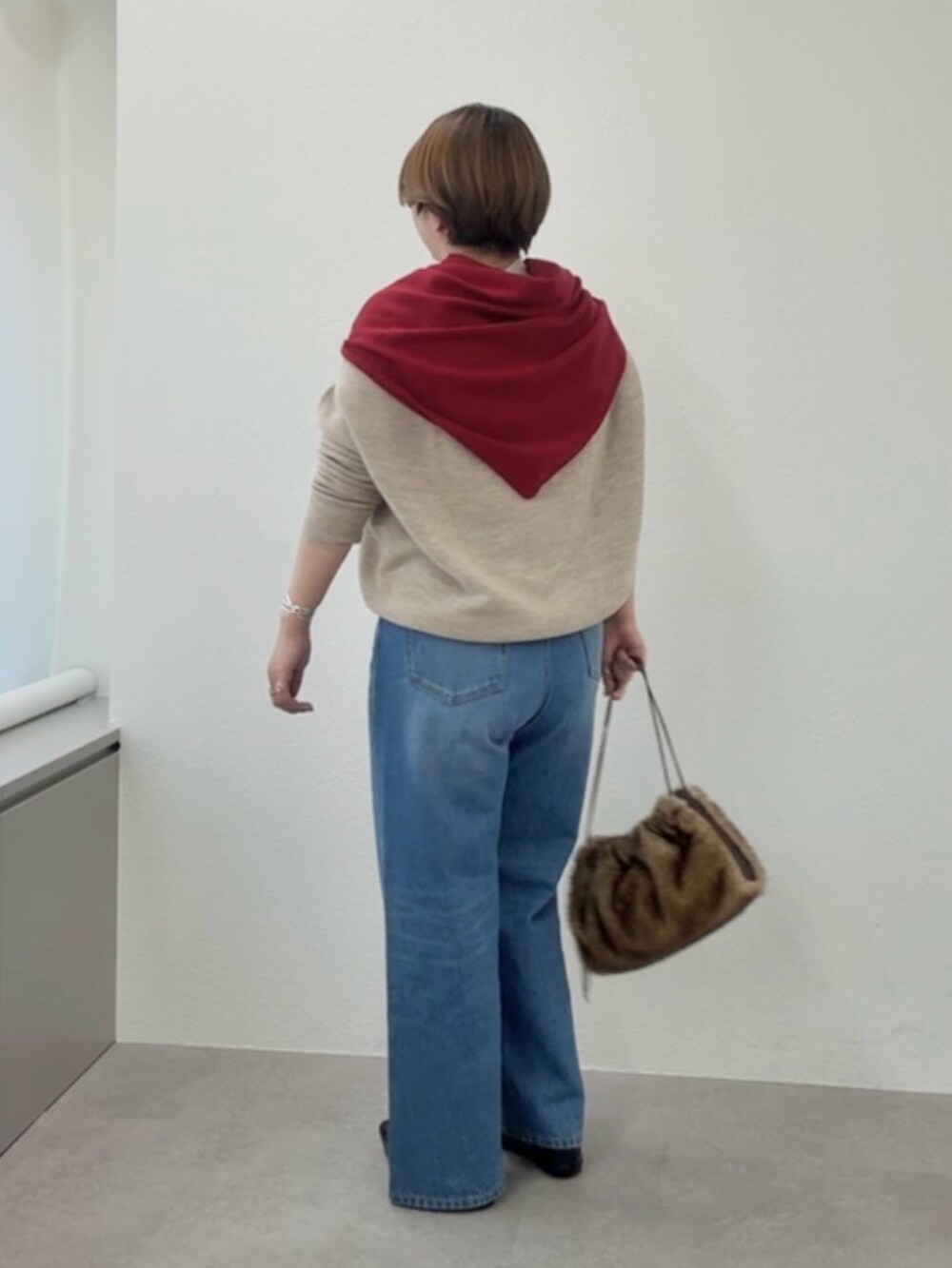 ベージュ系のニット/セーター、ブルー系のデニムパンツ、レッド系のストール/ショールを着用したレディースの冬コーディネートの3枚目の写真