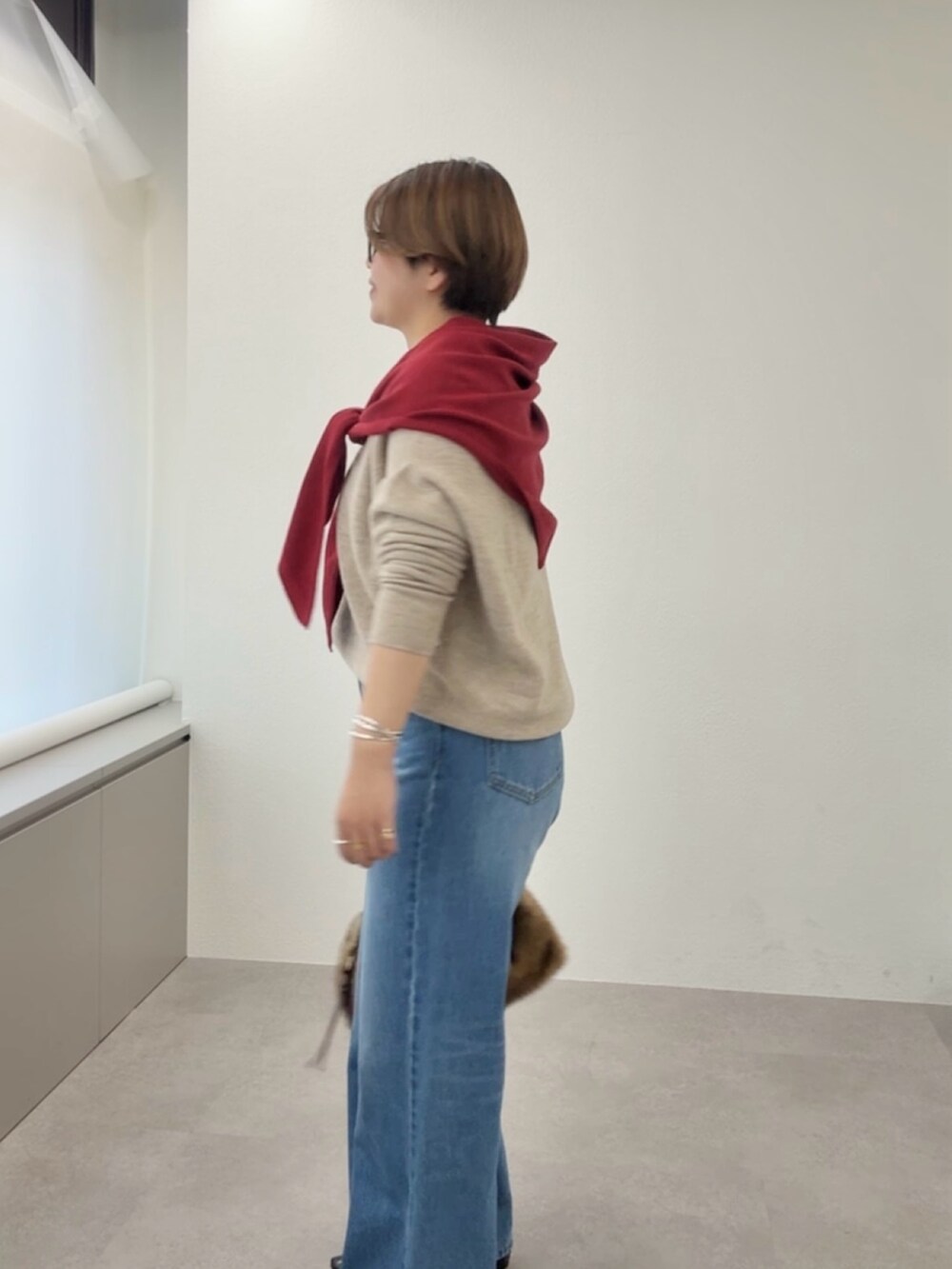 ベージュ系のニット/セーター、ブルー系のデニムパンツ、レッド系のストール/ショールを着用したレディースの冬コーディネートの6枚目の写真