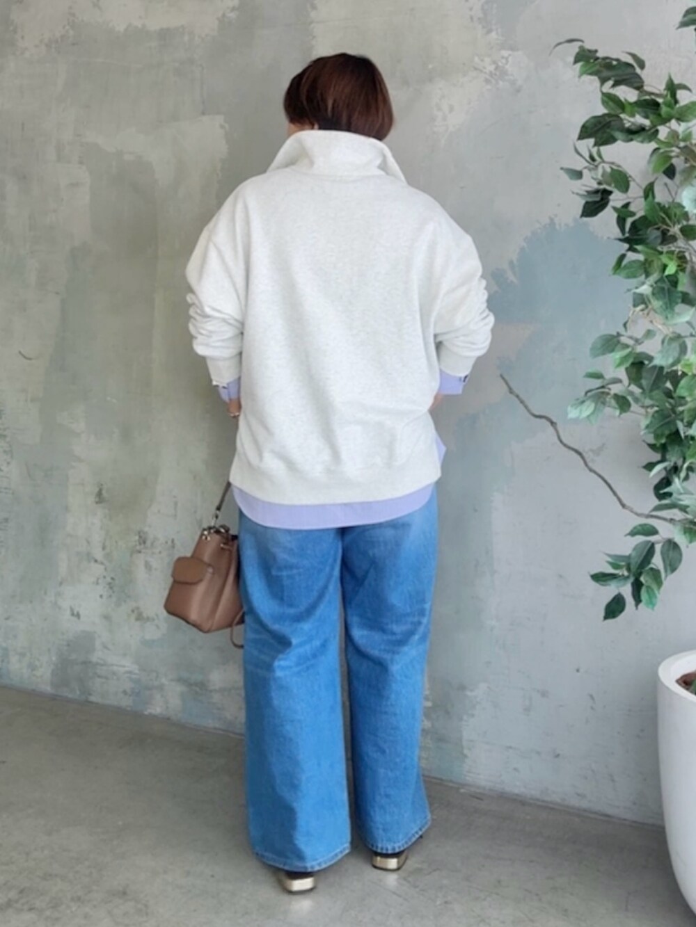 グレー系のスウェット、ブルー系のデニムパンツ、ブラウン系のショルダーバッグを着用したレディースの冬コーディネートの2枚目の写真