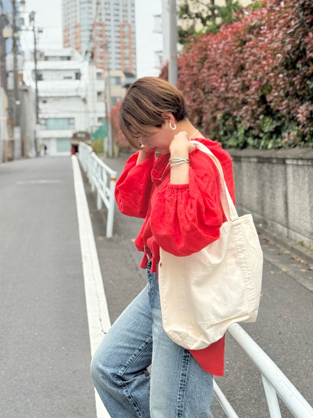 レッド系のシャツ/ブラウス、ブルー系のデニムパンツ、ホワイト系のハンドバッグを着用したレディースの春コーディネートの5枚目の写真