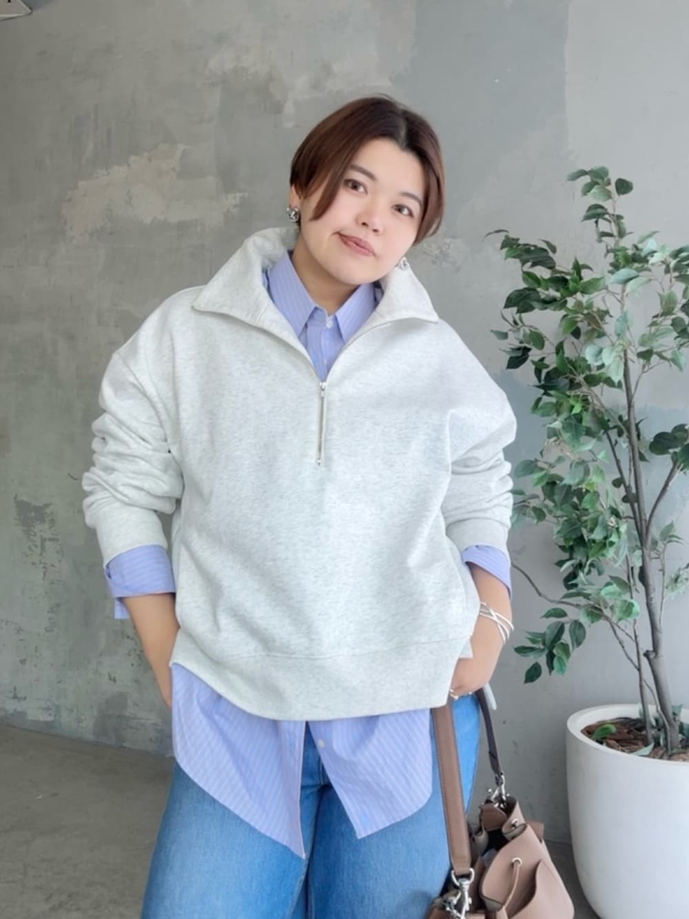 グレー系のスウェット、ブルー系のデニムパンツ、ブラウン系のショルダーバッグを着用したレディースの冬コーディネートの3枚目の写真