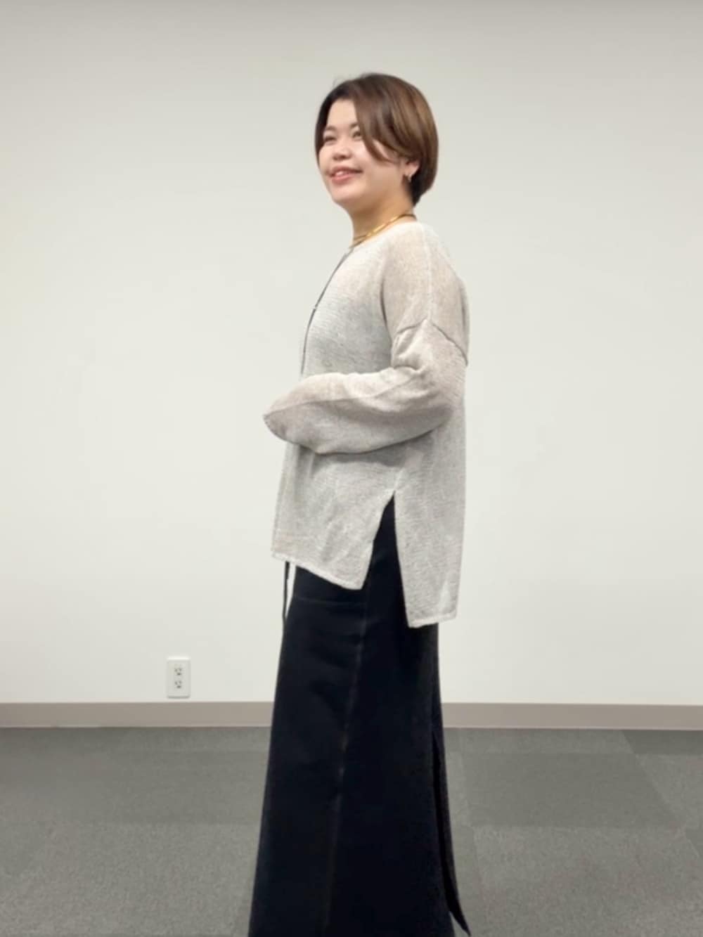 グレー系のニット/セーター、ブラック系のスカートを着用したレディースの春コーディネートの5枚目の写真