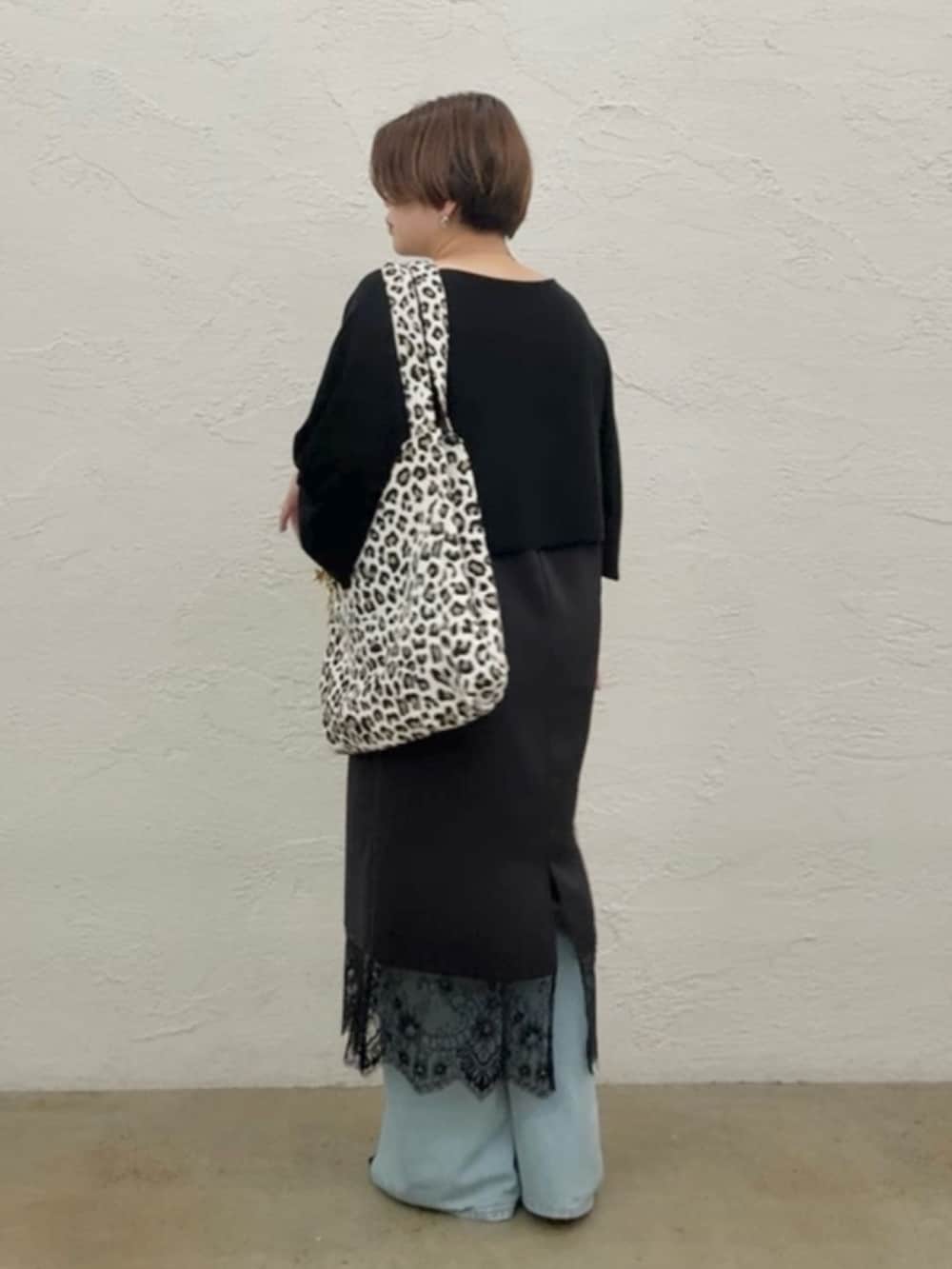 ブラック系のニット/セーター、ブラック系のワンピース、ブルー系のデニムパンツを着用したレディースの夏コーディネートの4枚目の写真