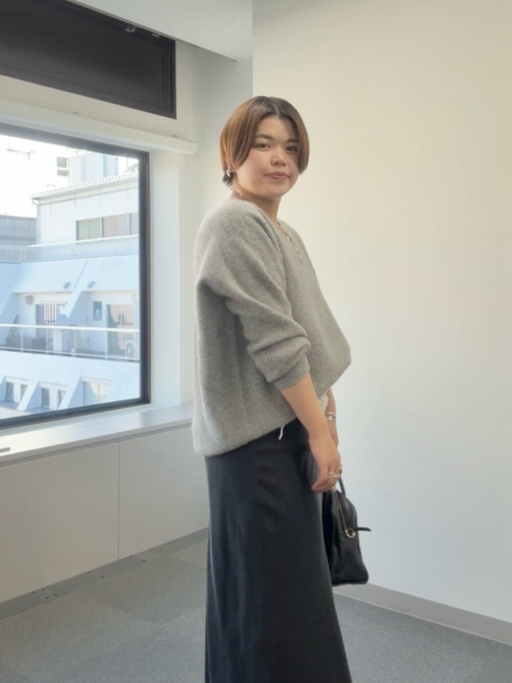 グレー系のニット/セーター、ブラック系のスカート、ホワイト系のストール/ショールを着用したレディースの冬コーディネートの4枚目の写真