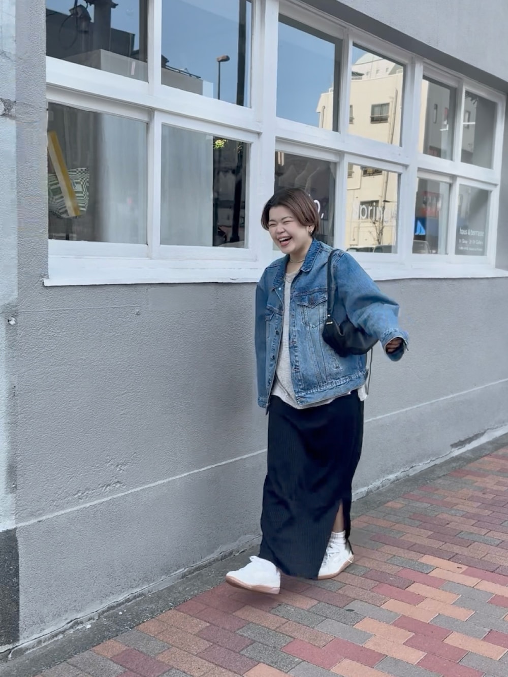 ブルー系のデニムジャケット、ブラック系のワンピース、グレー系のニット/セーターを着用したレディースの春コーディネートの2枚目の写真