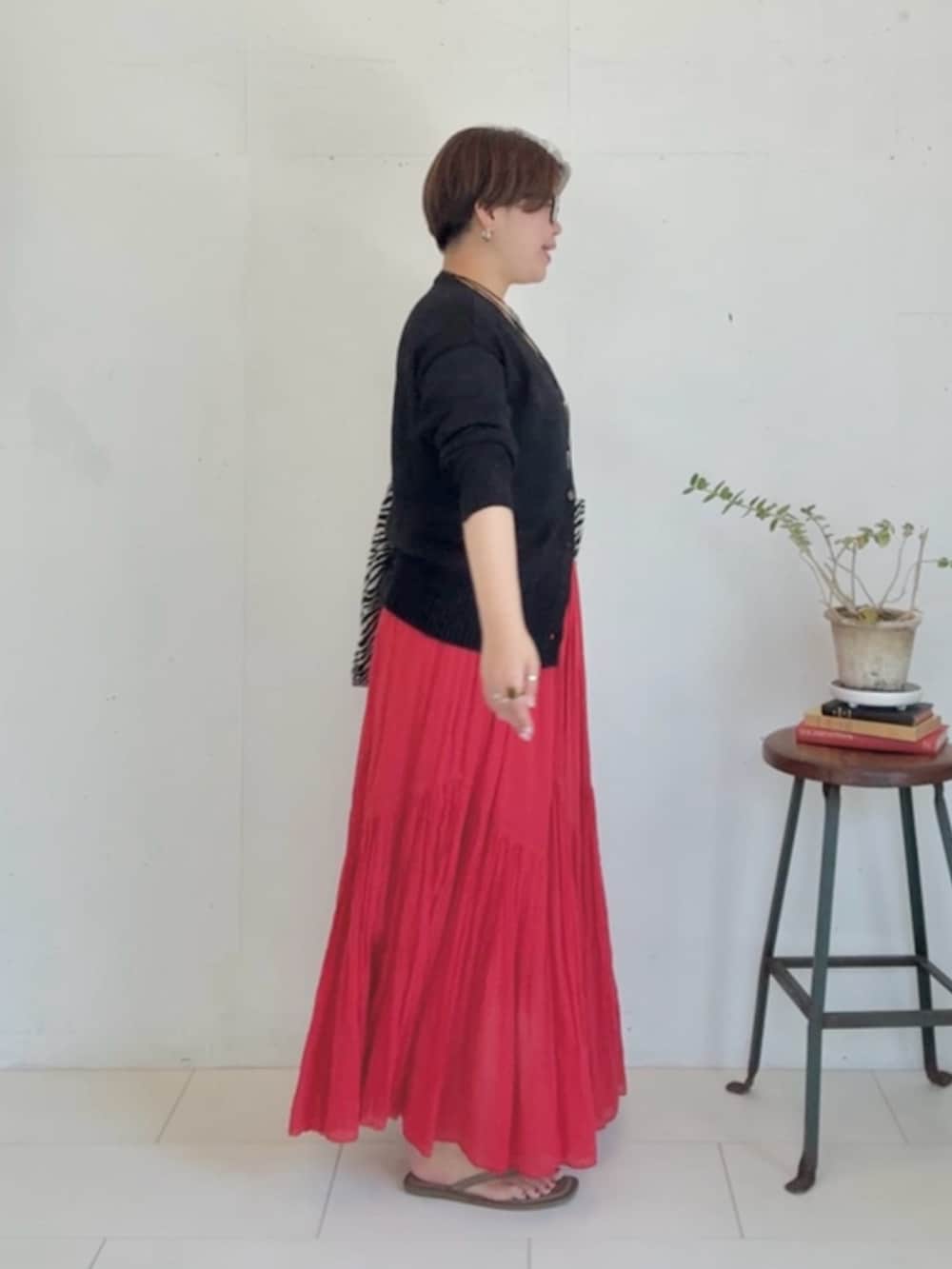 ブラック系のカーディガン/ボレロ、レッド系のスカート、ブラック系のトートバッグを着用したレディースの春コーディネートの2枚目の写真