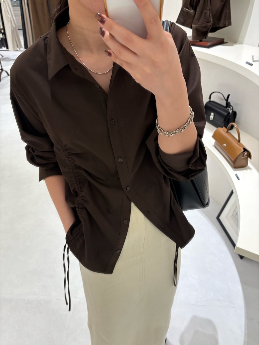 ホワイト系のスカート、ブラウン系のシャツ/ブラウス、ブラック系のショルダーバッグを着用したレディースの秋コーディネートの4枚目の写真