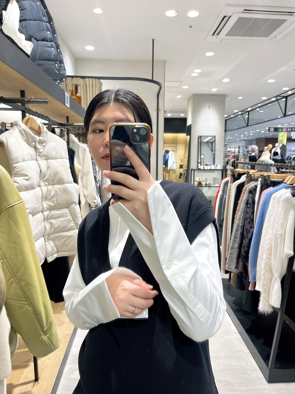 ブラック系のベスト、ホワイト系のTシャツ/カットソー、ブラック系のスカートを着用したレディースの冬コーディネートの2枚目の写真