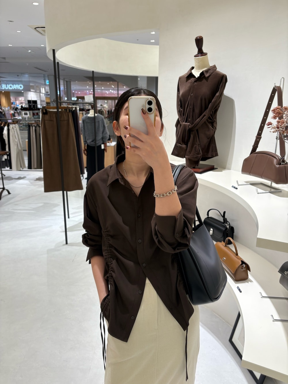 ホワイト系のスカート、ブラウン系のシャツ/ブラウス、ブラック系のショルダーバッグを着用したレディースの秋コーディネートの3枚目の写真