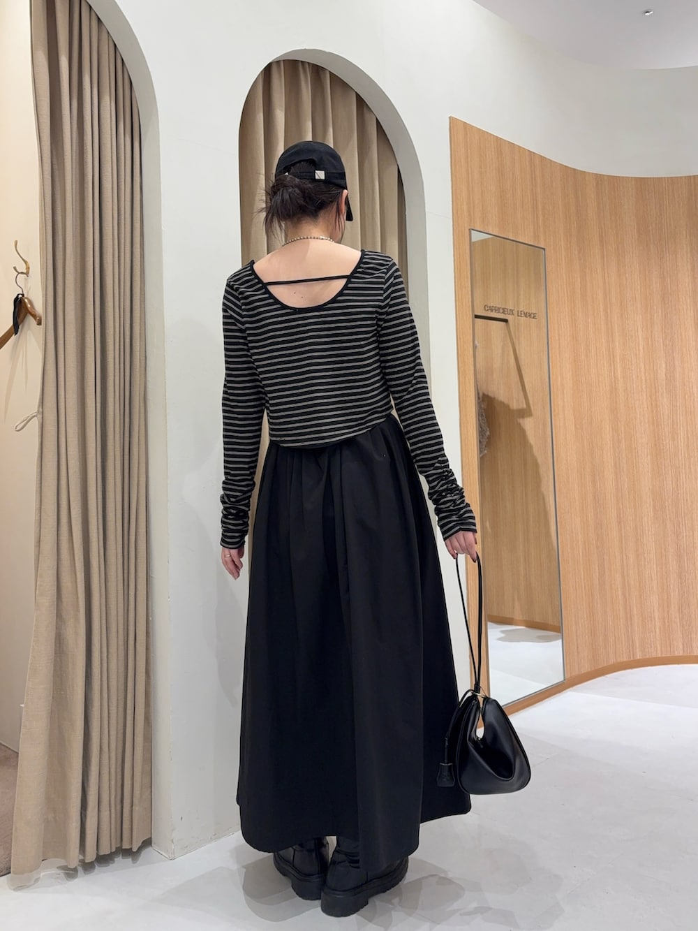 ブラック系のスカート、ブラック系のTシャツ/カットソー、ブラック系のショルダーバッグを着用したレディースの冬コーディネートの3枚目の写真