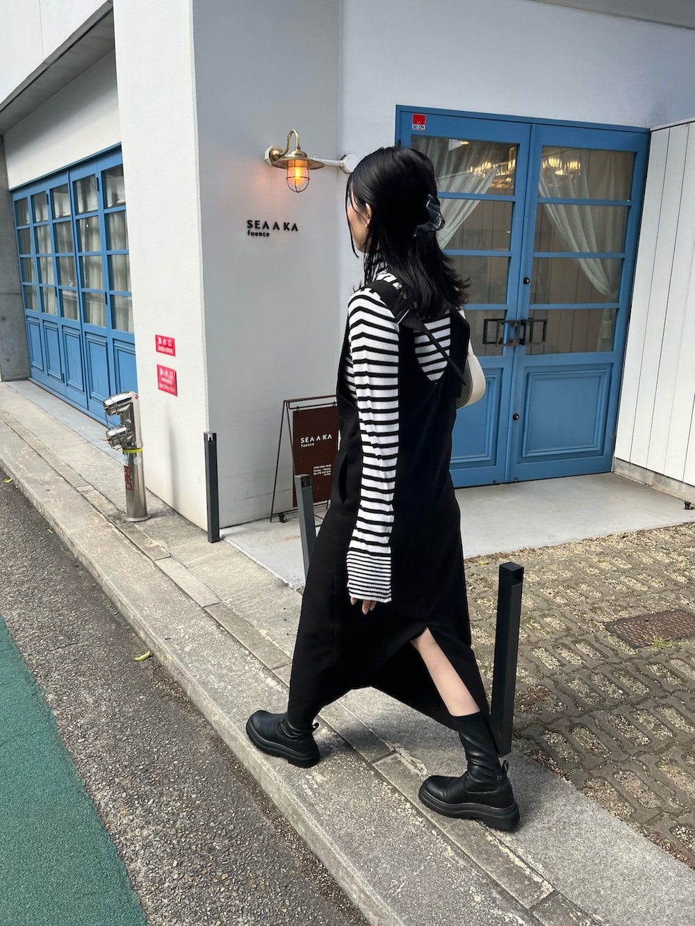 ブラック系のジャンパースカート、ホワイト系のニット/セーター、ホワイト系のショルダーバッグを着用したレディースの秋コーディネートの3枚目の写真