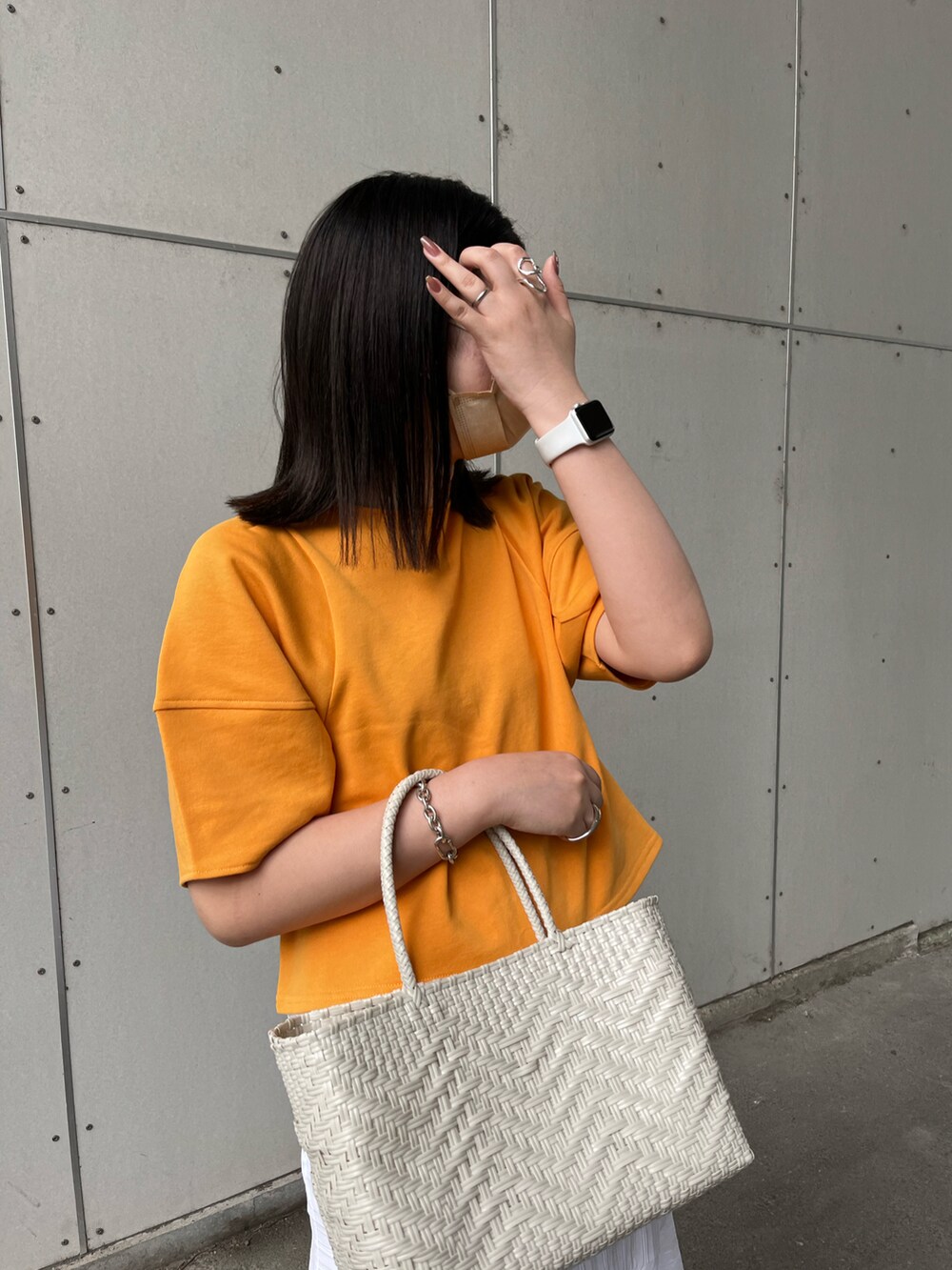 オレンジ系のTシャツ/カットソー、ホワイト系のトートバッグ、ホワイト系のスカートを着用したレディースの春コーディネートの2枚目の写真