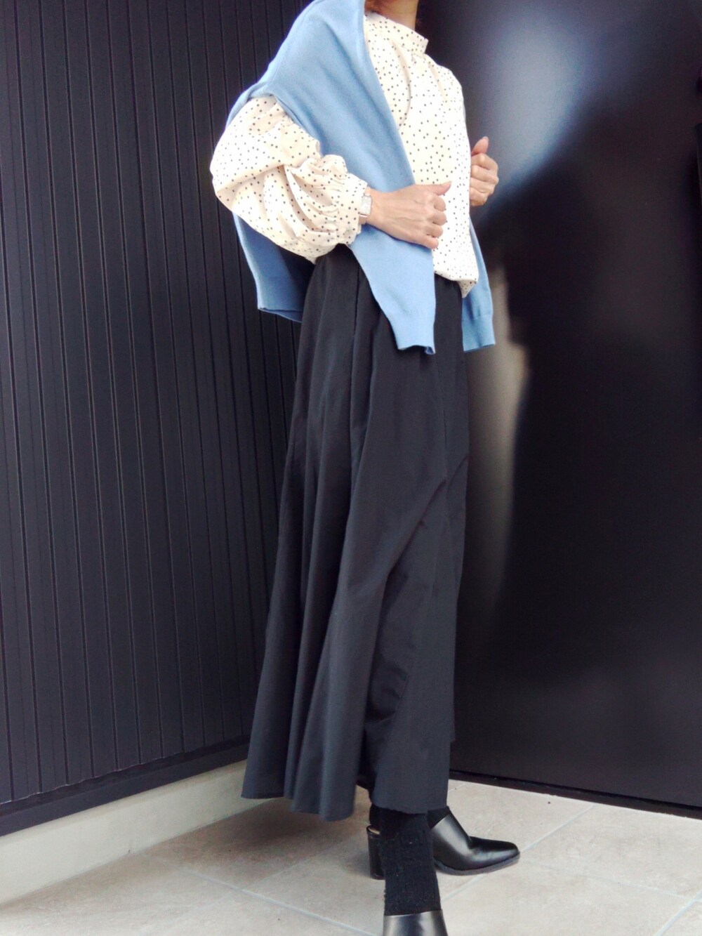 ブルー系のニット/セーター、ホワイト系のシャツ/ブラウス、ブラック系のスカートを着用したレディースの春コーディネートの2枚目の写真