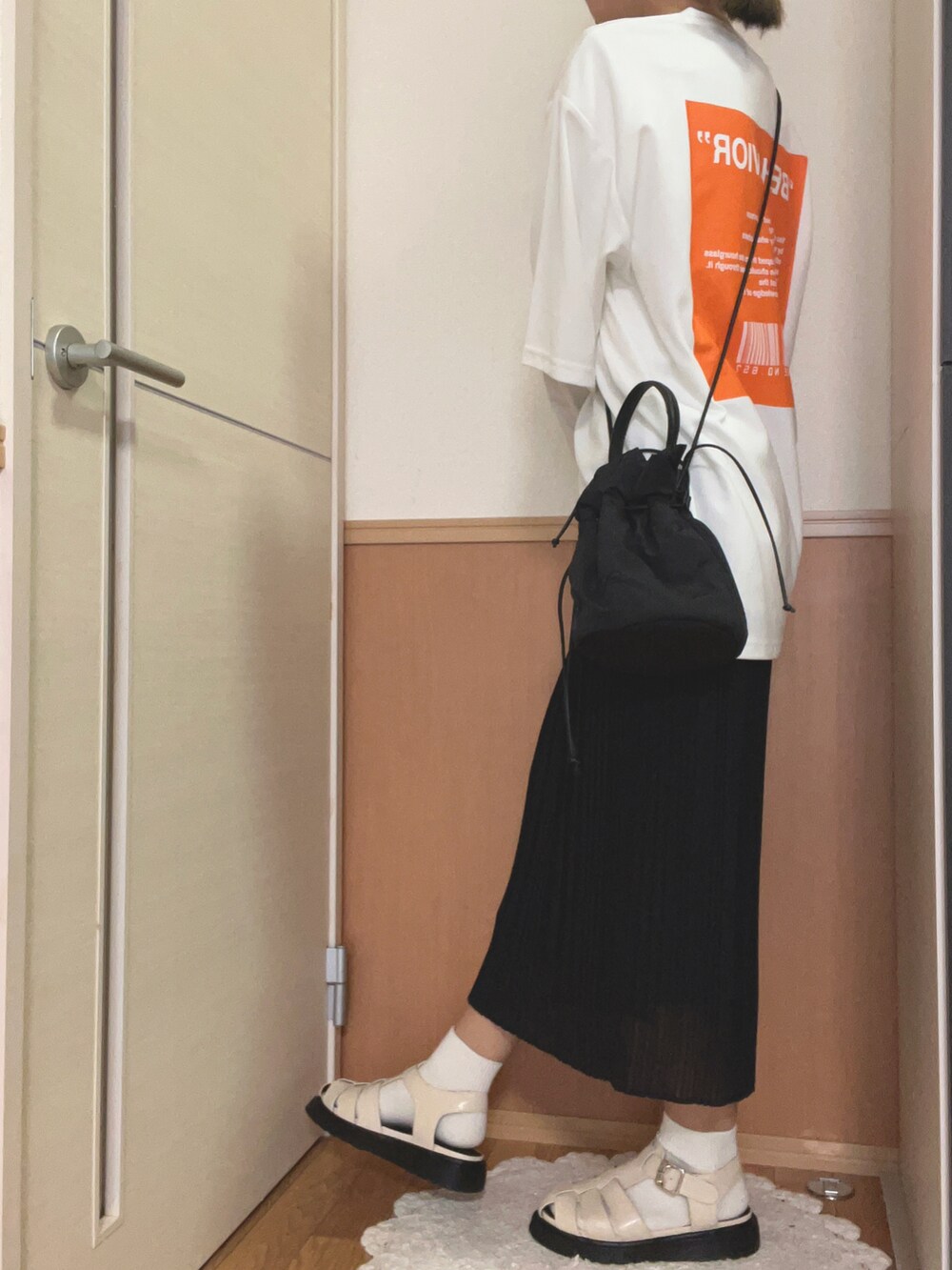 ホワイト系のサンダル、ブラック系のスカート、ブラック系のハンドバッグを着用したレディースの夏コーディネートの2枚目の写真