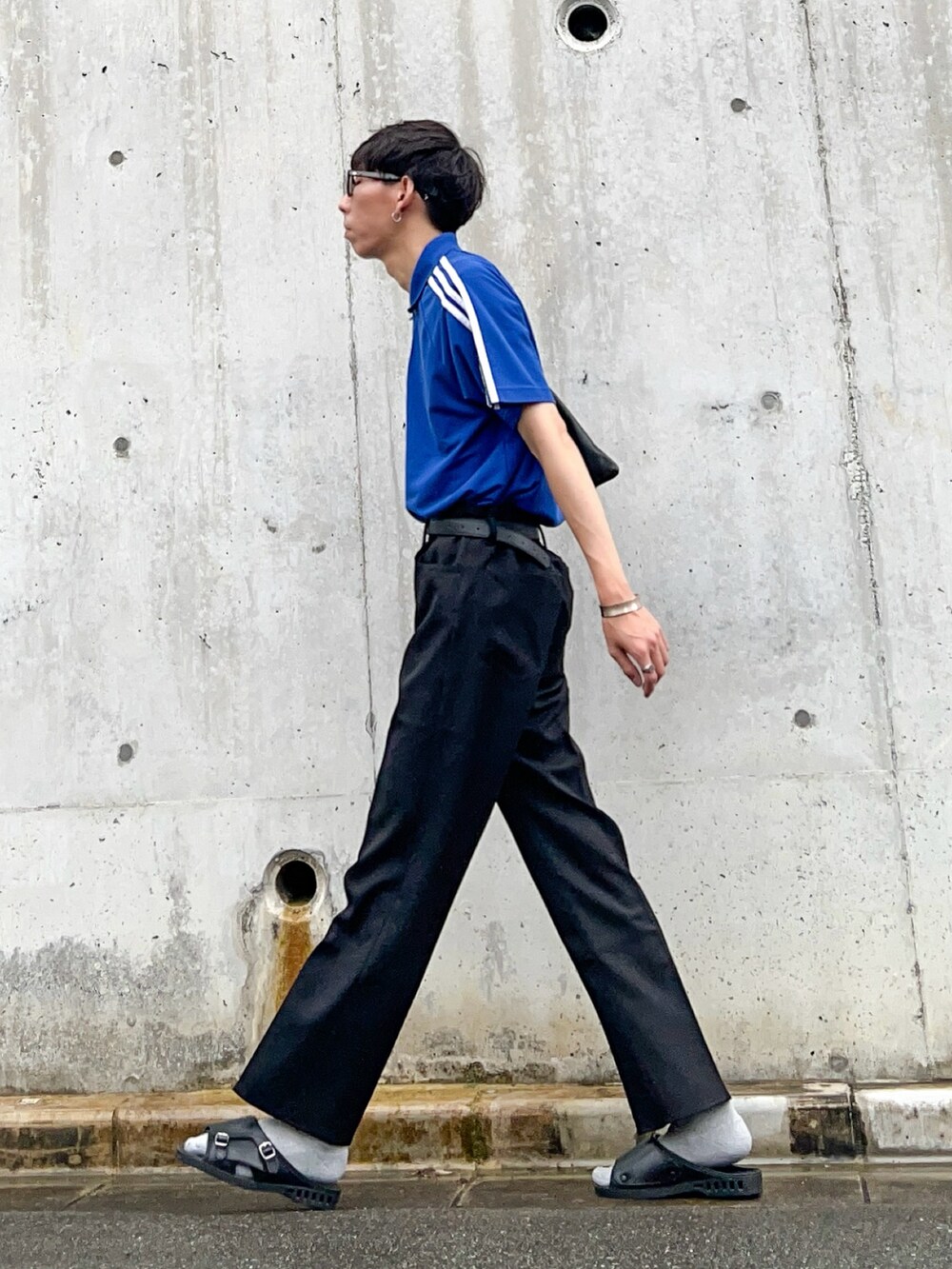 ブルー系のポロシャツ、ブラック系のスラックス、ブラック系のサンダルを着用したメンズの夏コーディネートの2枚目の写真