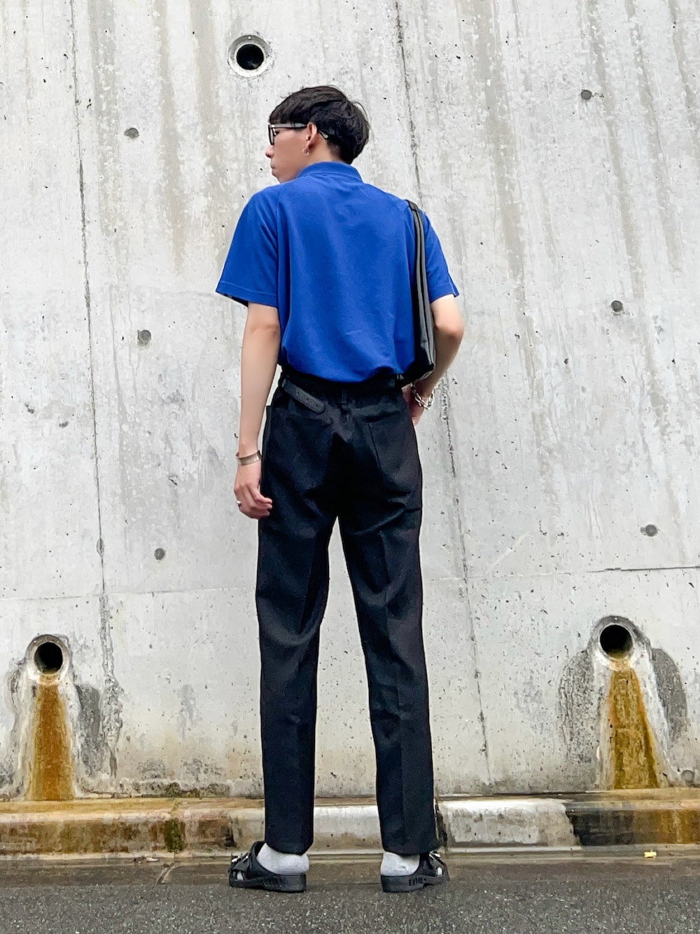 ブルー系のポロシャツ、ブラック系のスラックス、ブラック系のサンダルを着用したメンズの夏コーディネートの3枚目の写真