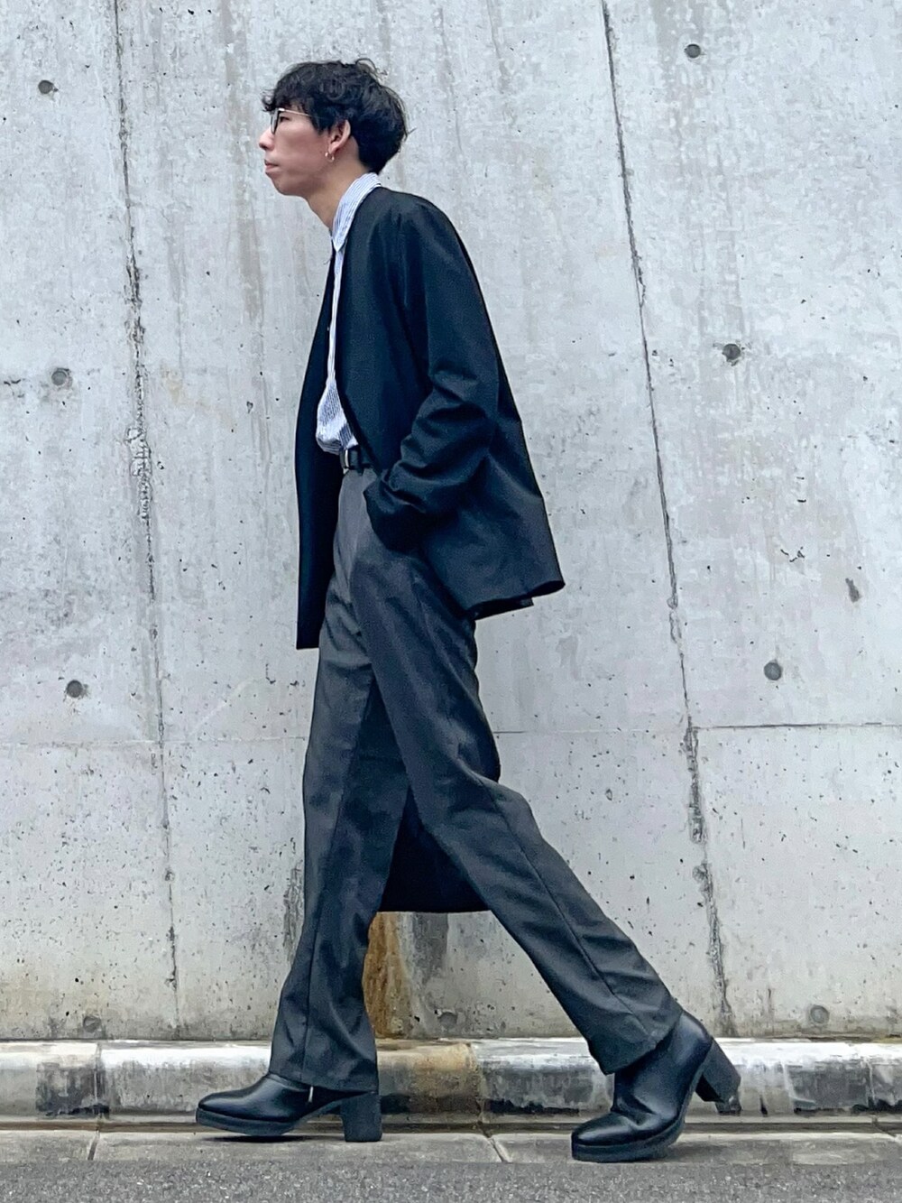 ブラック系のノーカラーコート、グレー系のスラックス、ブラック系のブーツを着用したメンズの春コーディネートの3枚目の写真