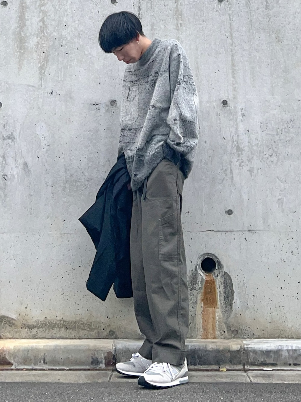 ブラック系のステンカラーコート、グレー系のニット/セーター、グリーン系のその他パンツを着用したメンズの冬コーディネートの2枚目の写真