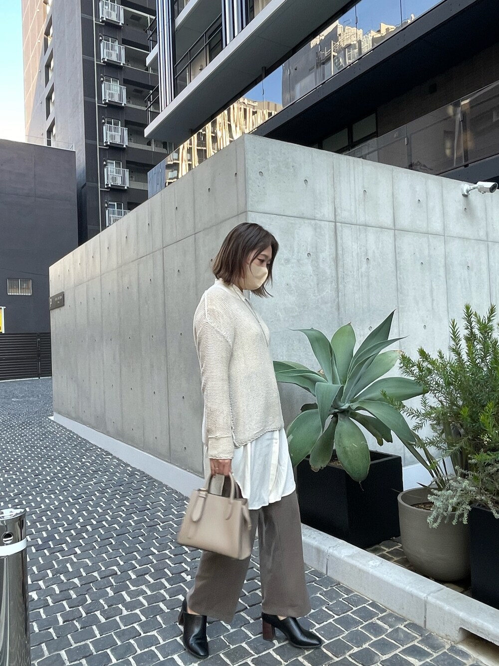 ブラック系のブーティ、ベージュ系のニット/セーター、ホワイト系のシャツ/ブラウスを着用したレディースの秋コーディネートの2枚目の写真