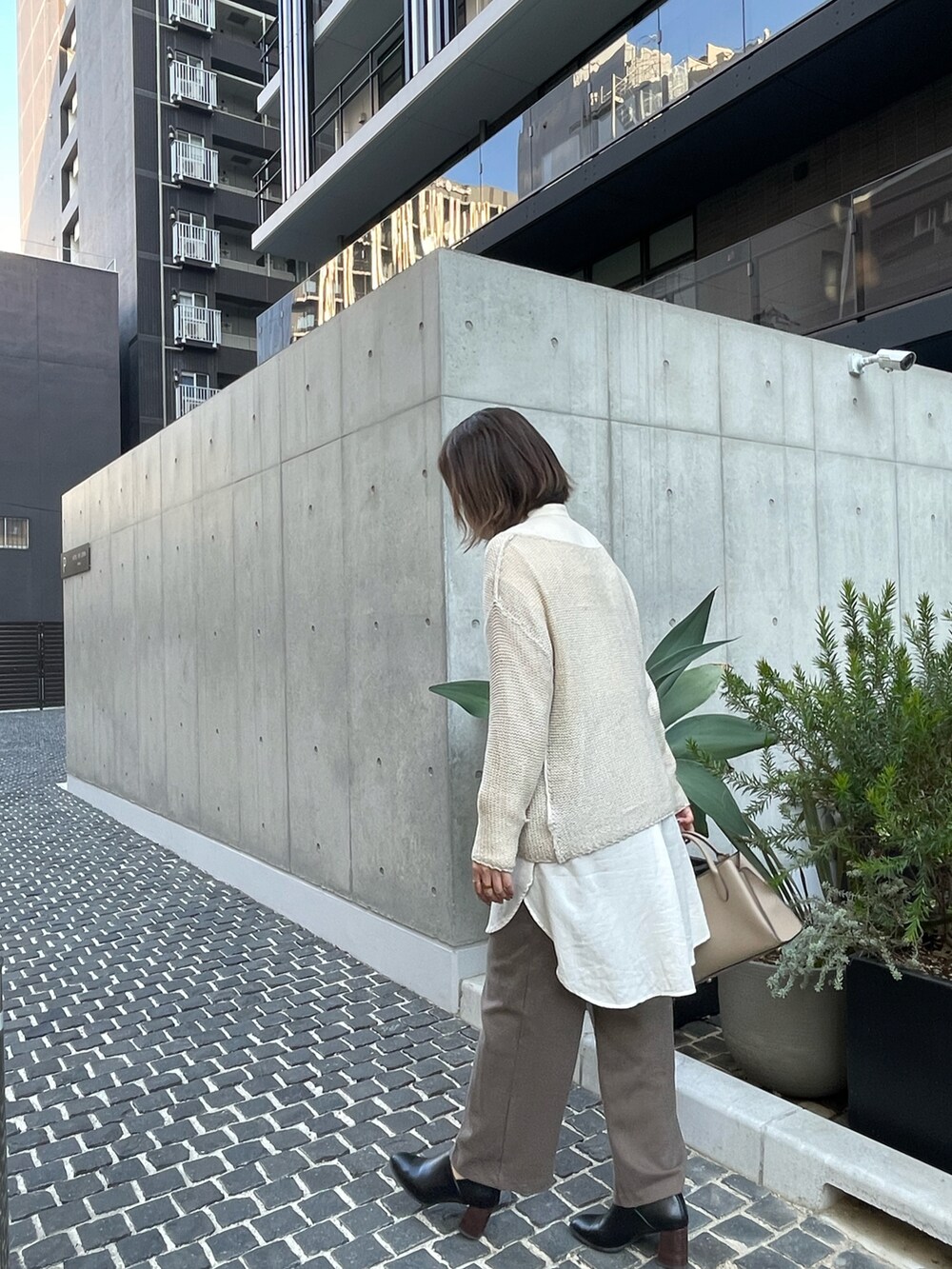 ブラック系のブーティ、ベージュ系のニット/セーター、ホワイト系のシャツ/ブラウスを着用したレディースの秋コーディネートの3枚目の写真