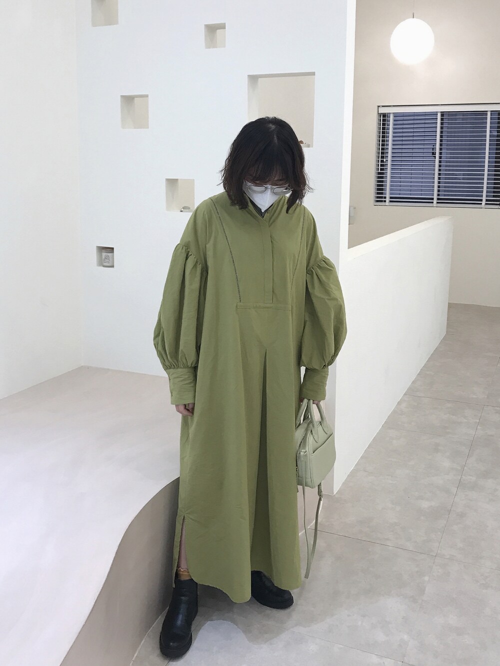 グリーン系のショルダーバッグ、グリーン系のワンピース、オレンジ系のリングを着用したレディースの冬コーディネートの2枚目の写真