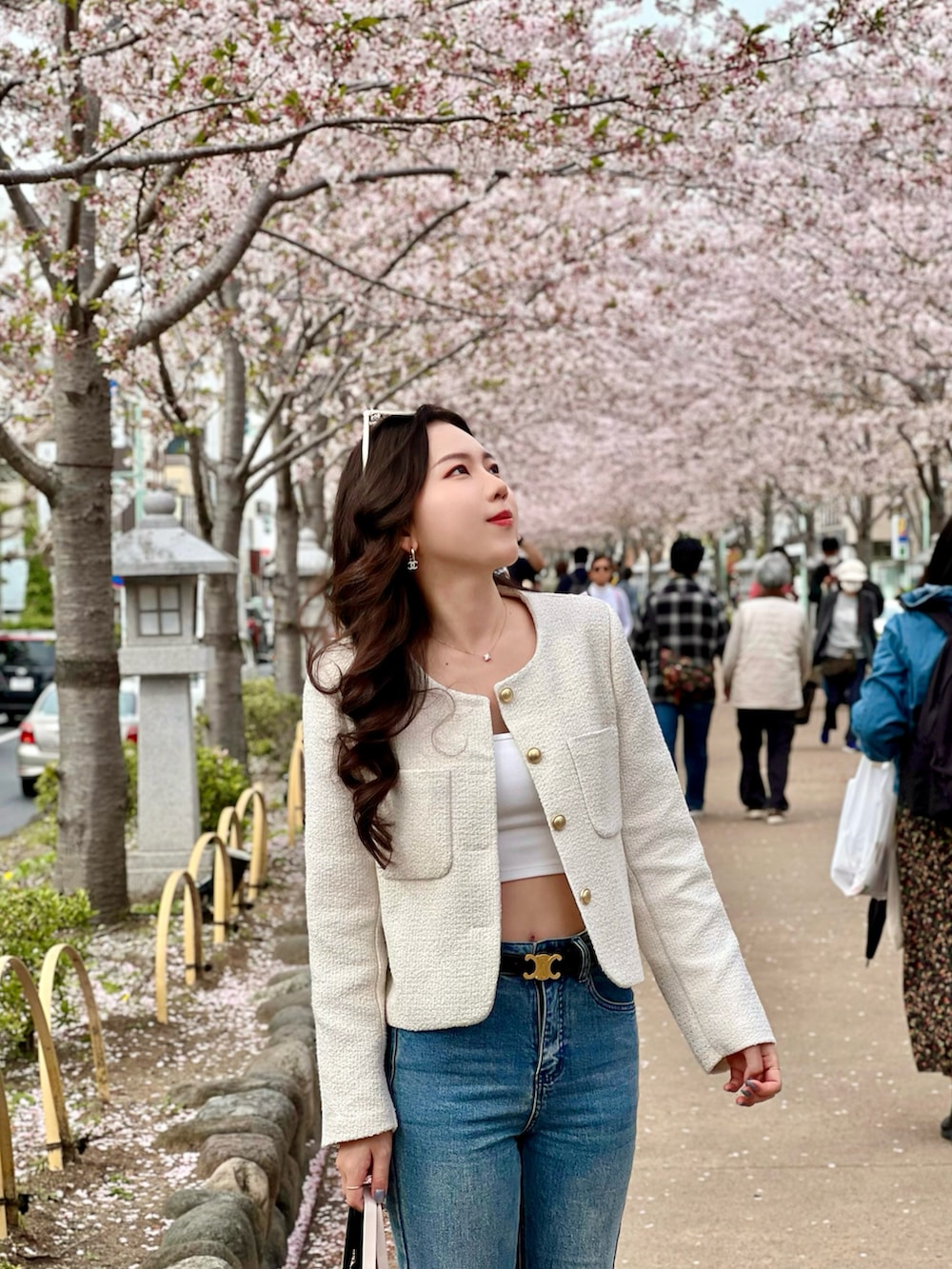 ベージュ系のハンドバッグ、ブラック系のベルト、ゴールド系のピアス（両耳用）を着用したレディースの春コーディネートの2枚目の写真