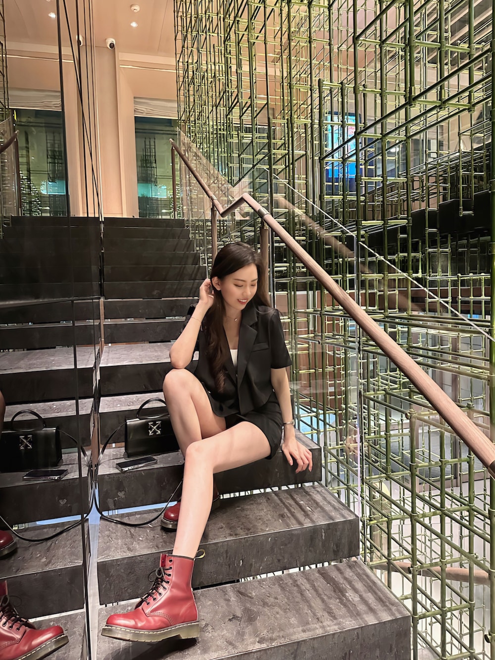 レッド系のブーツ、ブラック系のショルダーバッグを着用したレディースの秋コーディネートの2枚目の写真