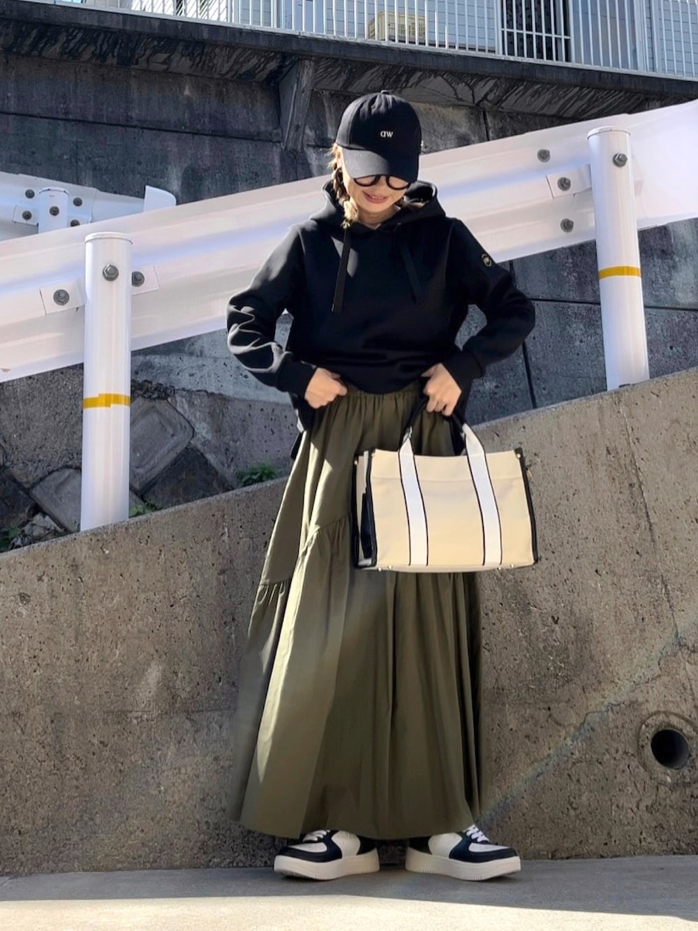 ブラック系のパーカー、ブラウン系のバッグ、ホワイト系のスニーカーを着用したレディースの秋コーディネートの3枚目の写真