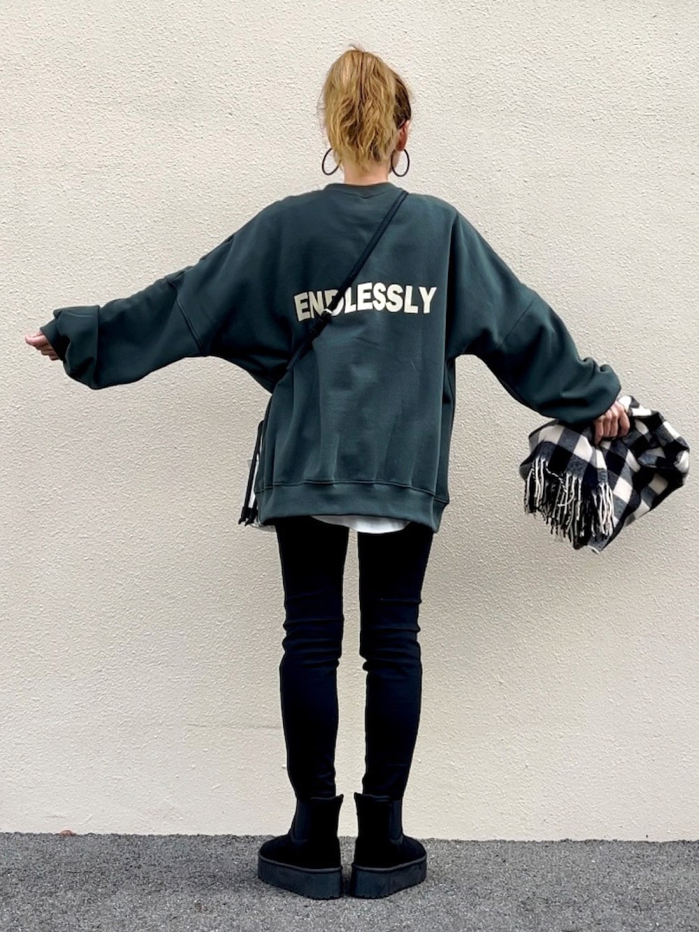 グリーン系のスウェット、ブラック系のブーツ、シルバー系のハンドバッグを着用したレディースの秋コーディネートの4枚目の写真