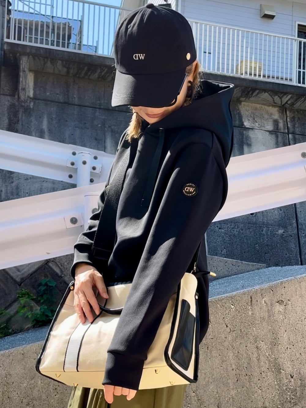 ブラック系のパーカー、ブラウン系のバッグ、ホワイト系のスニーカーを着用したレディースの秋コーディネートの5枚目の写真