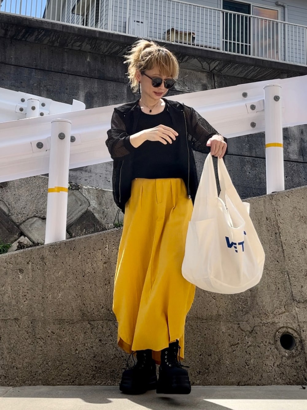 ブラック系のパーカー、イエロー系のスカート、ホワイト系のバッグを着用したレディースの秋コーディネートの4枚目の写真