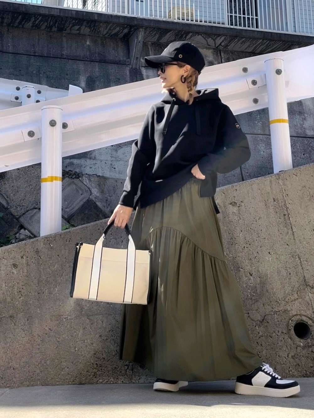 ブラック系のパーカー、ブラウン系のバッグ、ホワイト系のスニーカーを着用したレディースの秋コーディネートの4枚目の写真