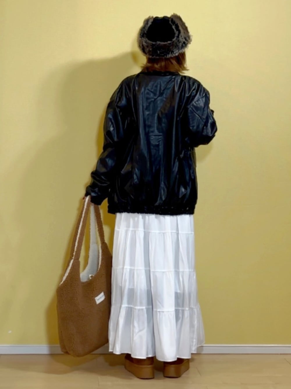 ブラック系のブルゾン、ホワイト系のスカート、ホワイト系のネックレスを着用したレディースの冬コーディネートの3枚目の写真