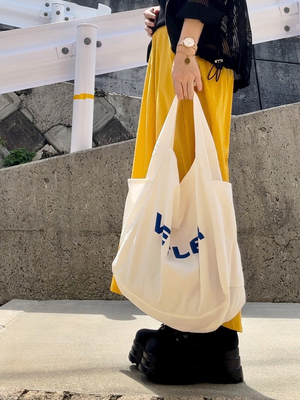 ブラック系のパーカー、イエロー系のスカート、ホワイト系のバッグを着用したレディースの秋コーディネートの2枚目の写真