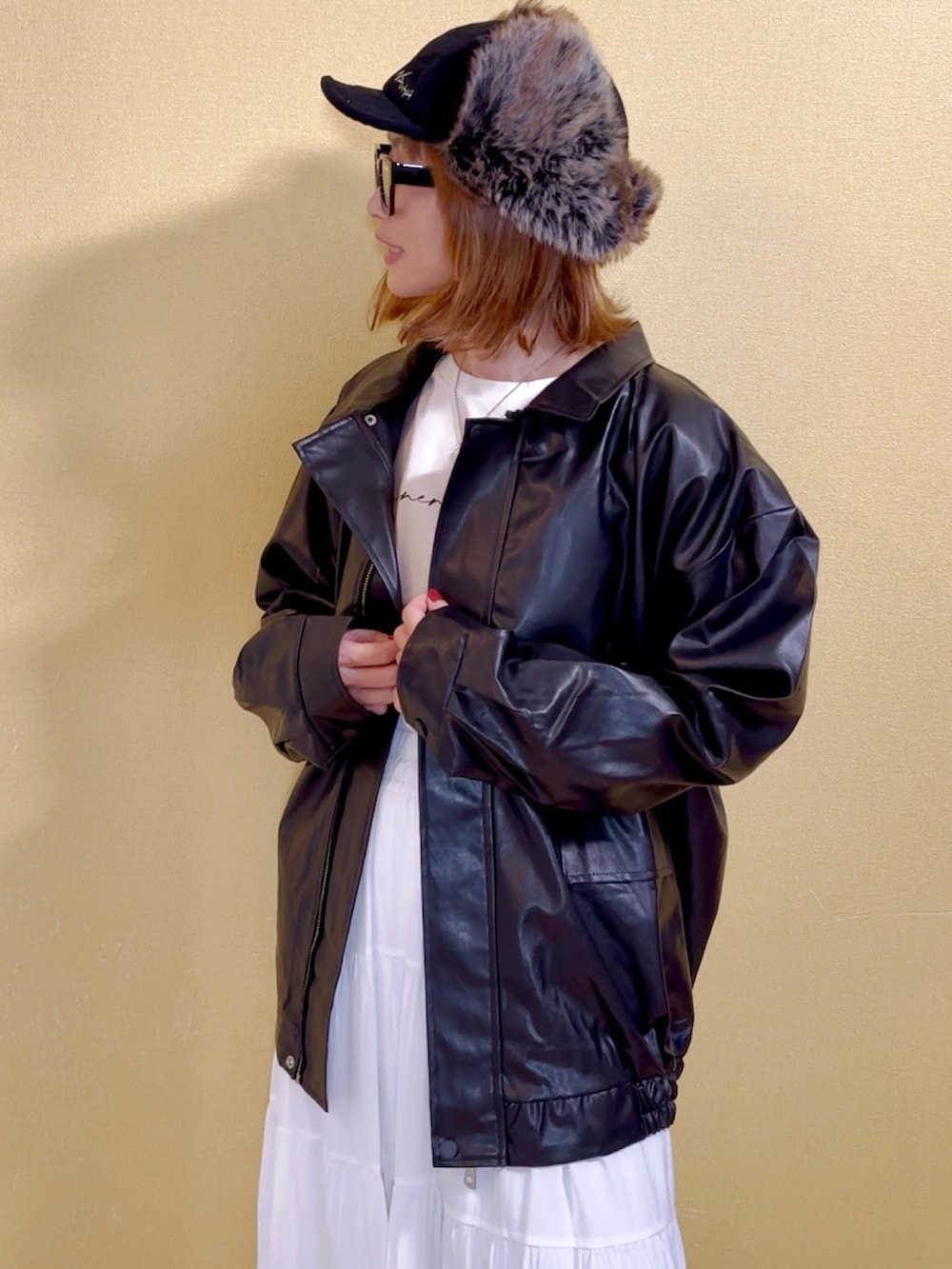 ブラック系のブルゾン、ホワイト系のスカート、ホワイト系のネックレスを着用したレディースの冬コーディネートの4枚目の写真