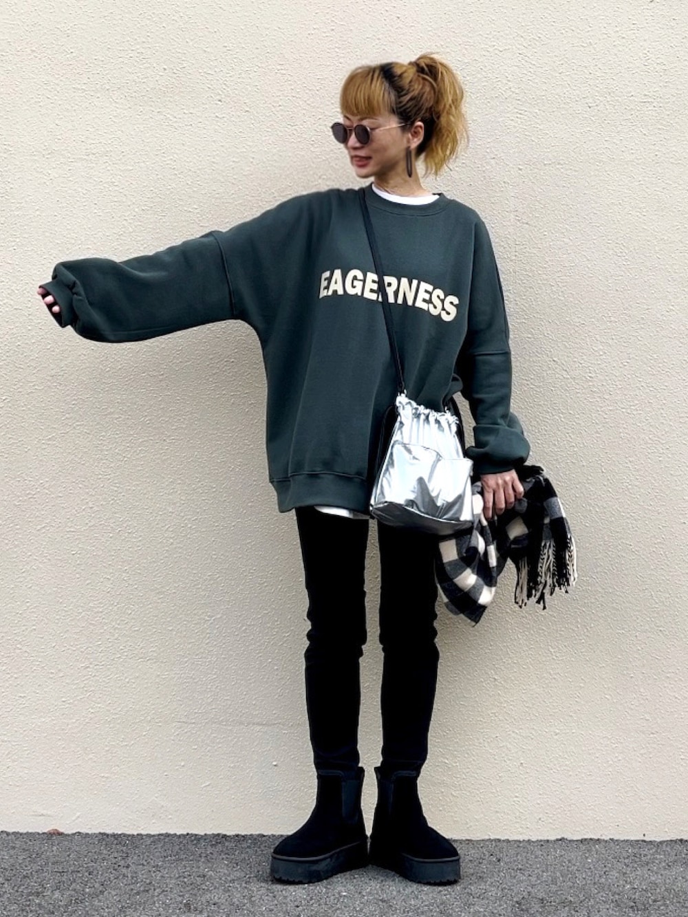 グリーン系のスウェット、ブラック系のブーツ、シルバー系のハンドバッグを着用したレディースの秋コーディネートの2枚目の写真