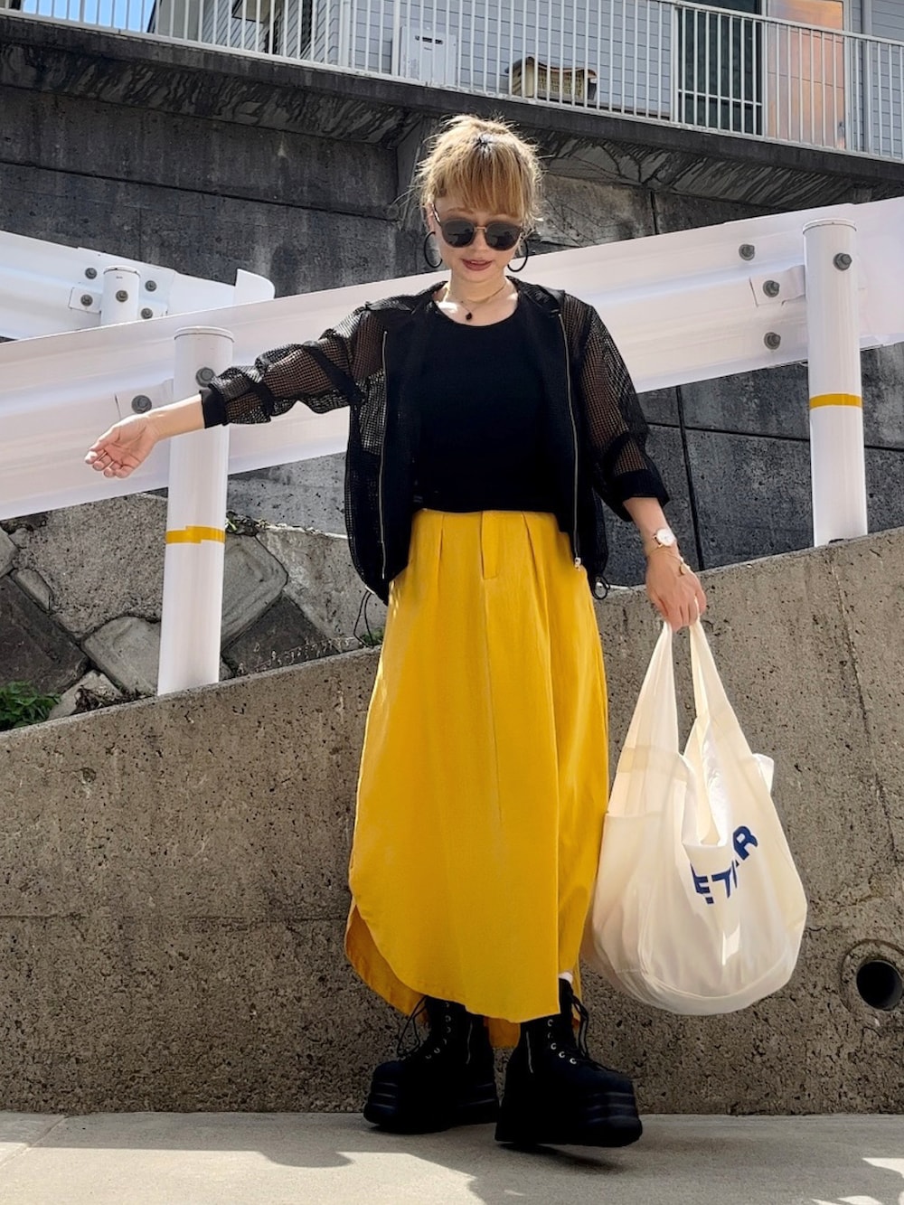 ブラック系のパーカー、イエロー系のスカート、ホワイト系のバッグを着用したレディースの秋コーディネートの5枚目の写真
