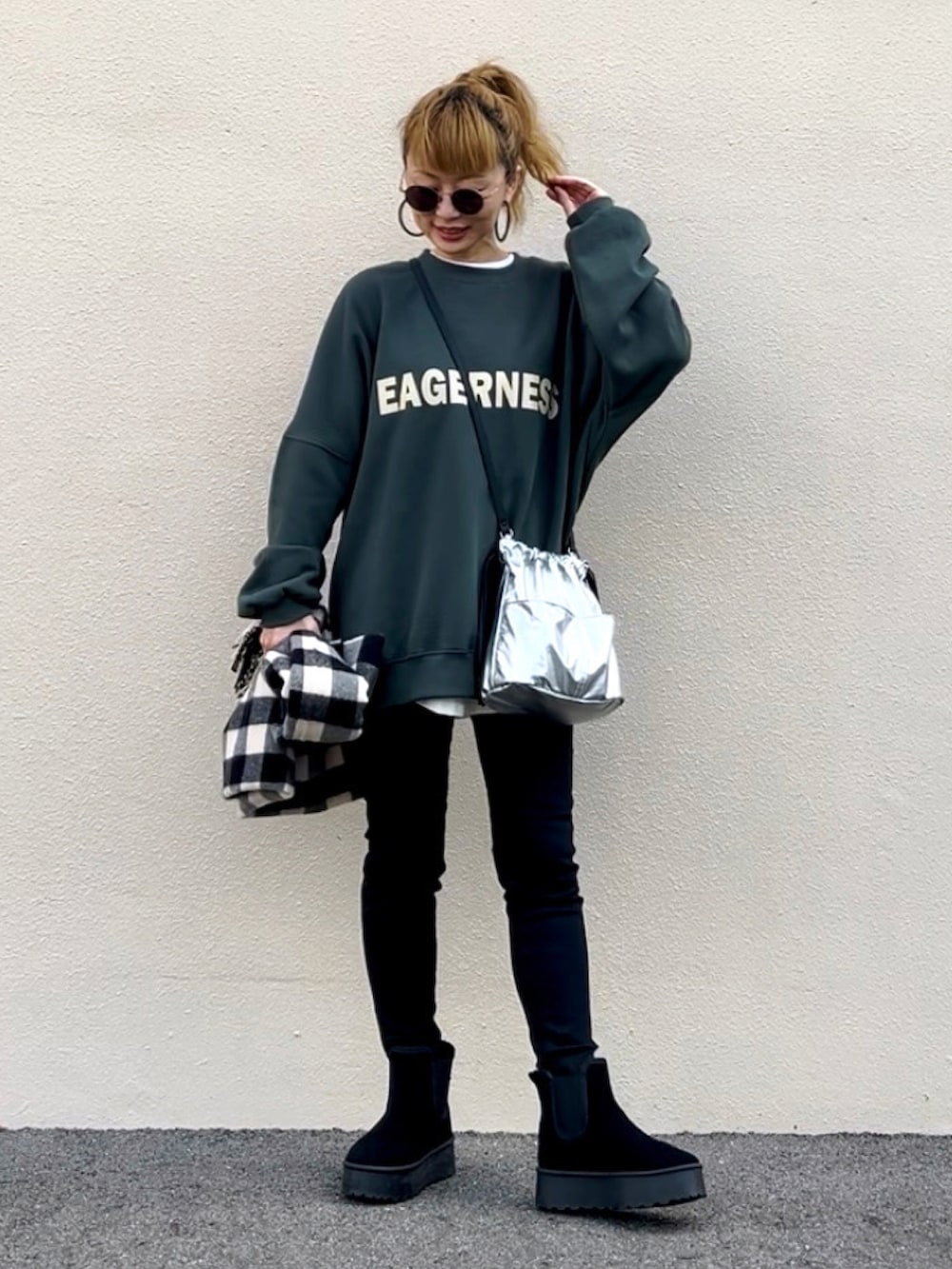 グリーン系のスウェット、ブラック系のブーツ、シルバー系のハンドバッグを着用したレディースの秋コーディネートの3枚目の写真