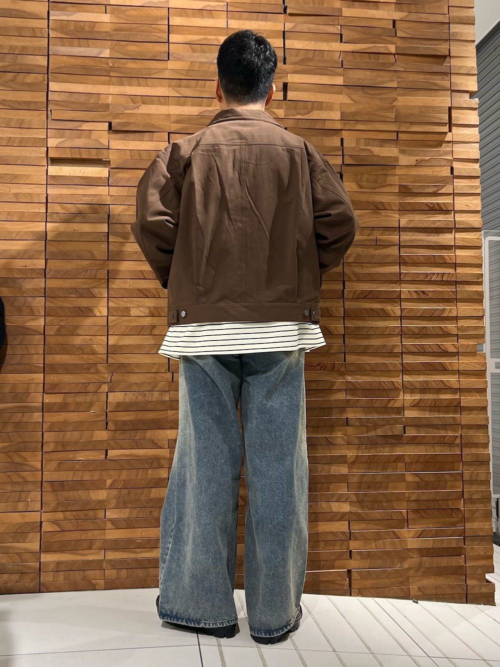 ホワイト系のTシャツ/カットソー、ブラウン系のブルゾン、ブルー系のデニムパンツを着用したメンズの春コーディネートの3枚目の写真