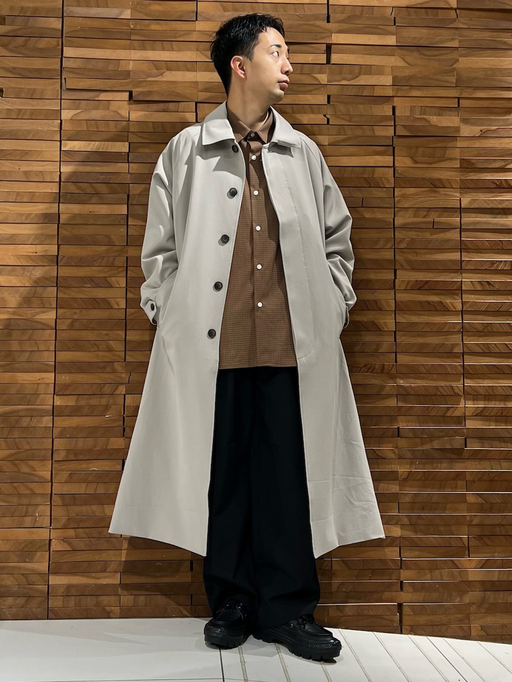 ブラウン系のシャツ/ブラウス、ベージュ系のステンカラーコート、ブラック系のその他パンツを着用したメンズの冬コーディネートの2枚目の写真