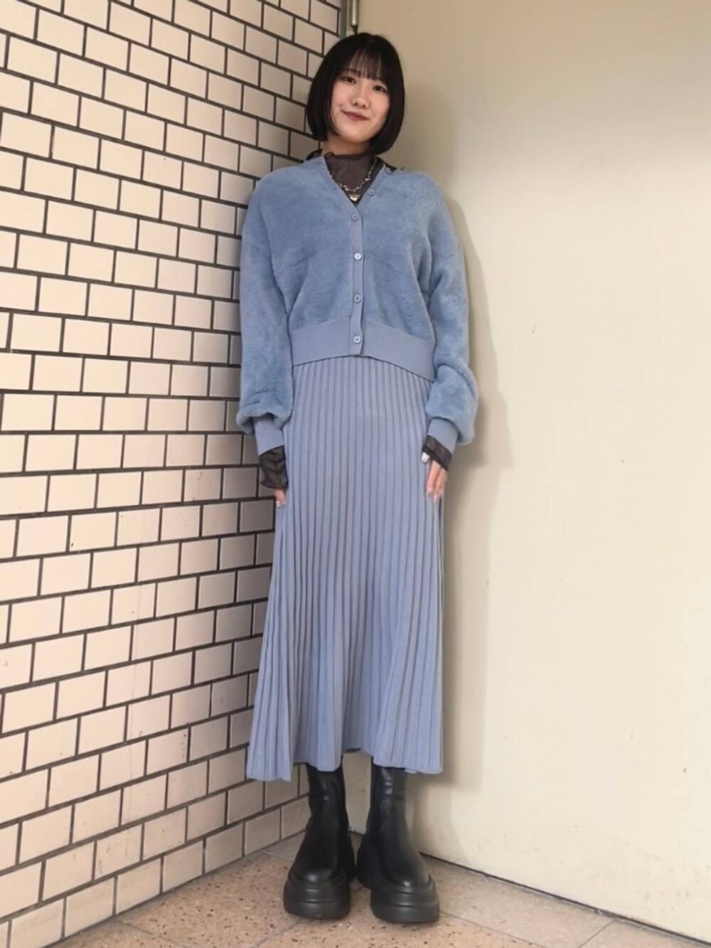 ホワイト系のブルゾン、ブラック系のブーツ、ブルー系のワンピースを着用したレディースの冬コーディネートの2枚目の写真