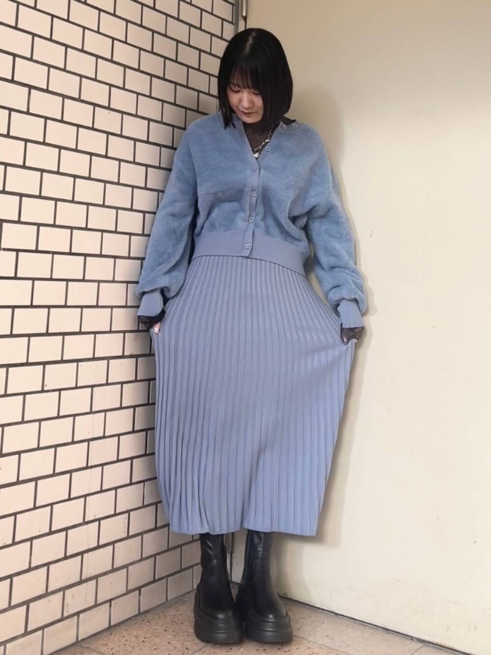 ホワイト系のブルゾン、ブラック系のブーツ、ブルー系のワンピースを着用したレディースの冬コーディネートの3枚目の写真