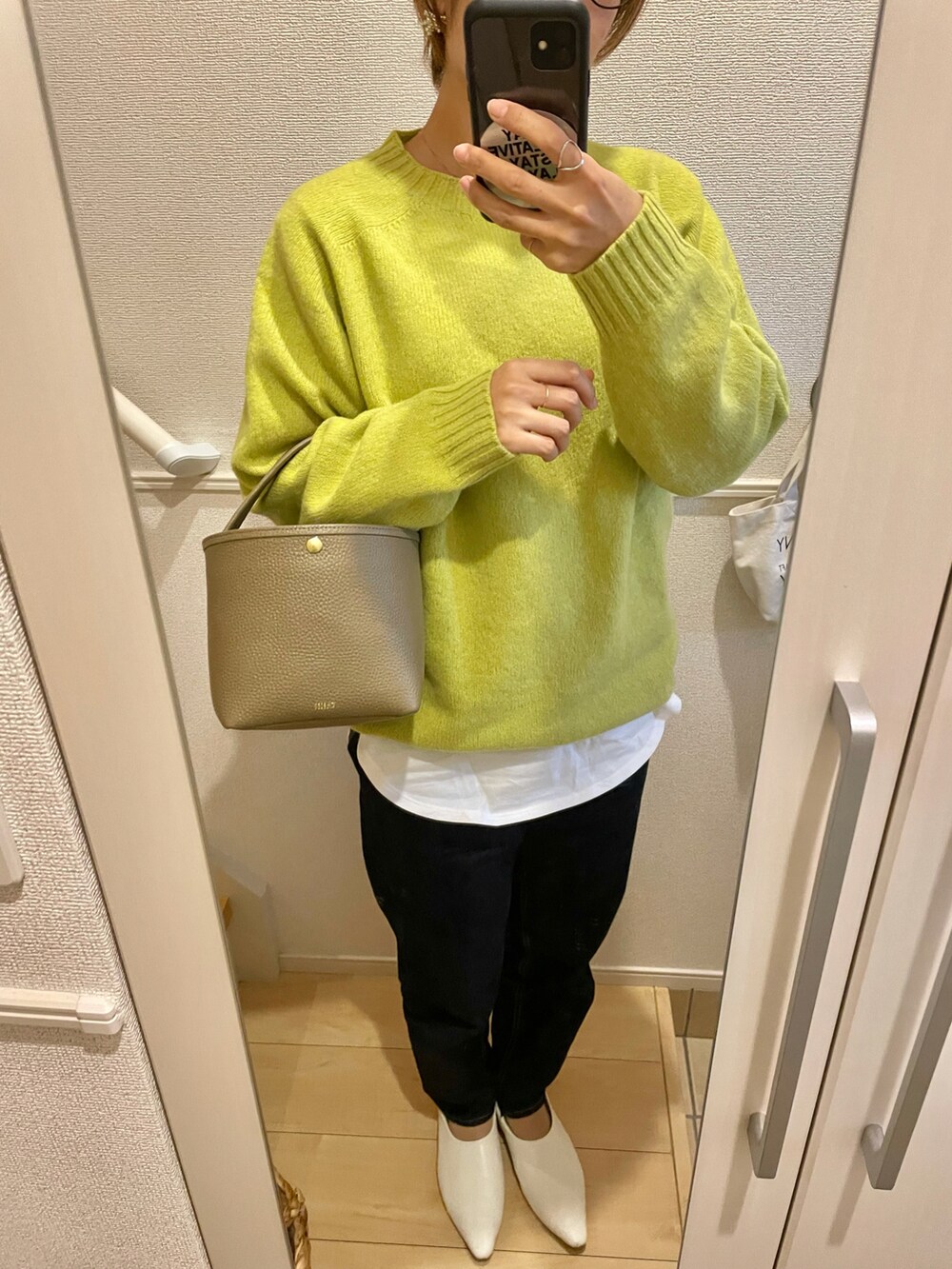 ブルー系のデニムパンツ、イエロー系のニット/セーター、ベージュ系のハンドバッグを着用したレディースの秋コーディネートの2枚目の写真