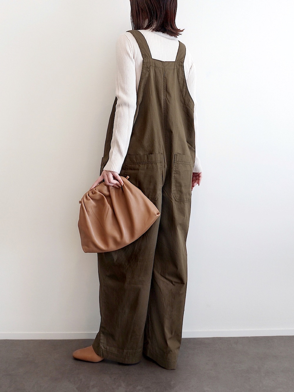 グリーン系のサロペット/オーバーオール、ホワイト系のニット/セーター、イエロー系のハンドバッグを着用したレディースの冬コーディネートの2枚目の写真