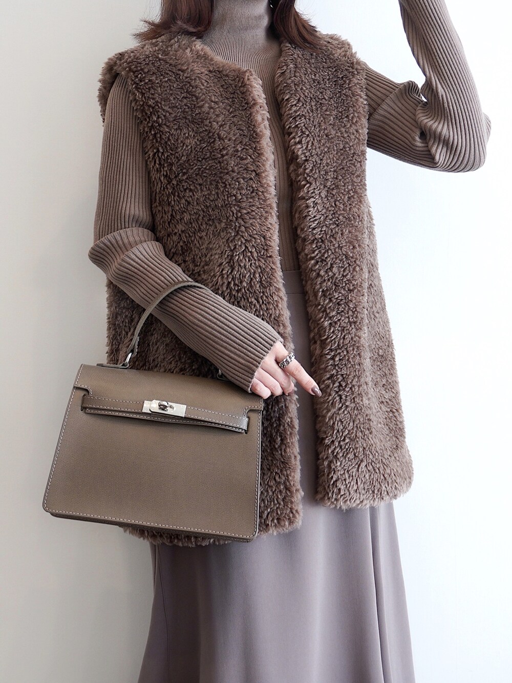 ベージュ系のニット/セーター、グレー系のパンプス、ブラウン系のベストを着用したレディースの秋コーディネートの2枚目の写真