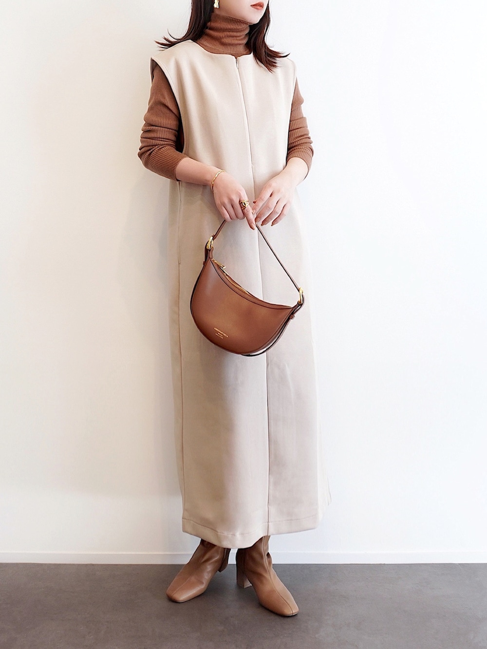 ベージュ系のワンピース、イエロー系のニット/セーター、ブラウン系のハンドバッグを着用したレディースの冬コーディネートの2枚目の写真