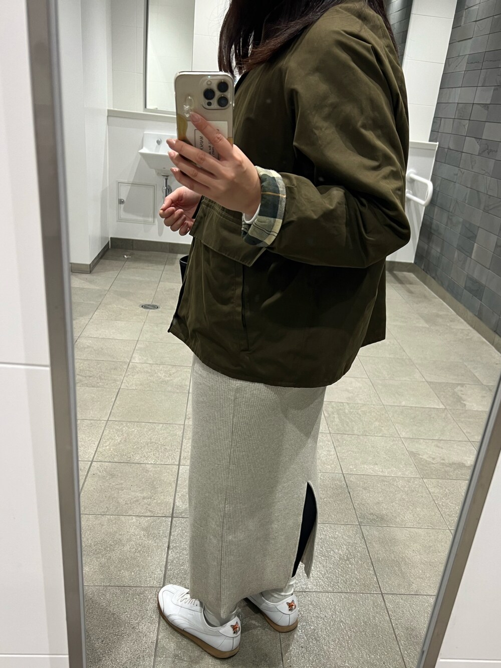 ブラック系のトートバッグ、ベージュ系のスカート、ホワイト系のスニーカーを着用したレディースの春コーディネートの2枚目の写真