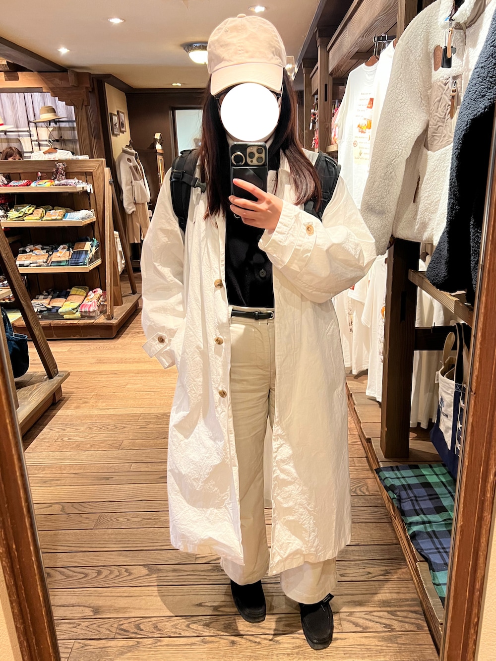 ホワイト系のステンカラーコート、ホワイト系のその他パンツ、ブラック系のベストを着用したレディースの春コーディネートの2枚目の写真